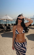 Mujer en la playa con conjunto de bikini y falda larga con estampado cebra azul marino