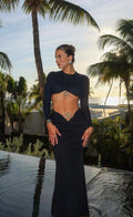 Mujer con conjunto negro de top crop manga larga y falda larga con apliques metálicos al atardecer