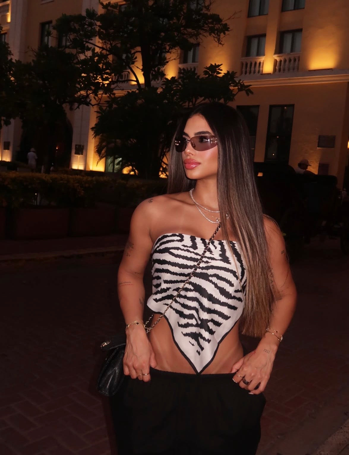 Mujer con top pañuelo estampado cebra blanco y negro y pantalón negro de noche